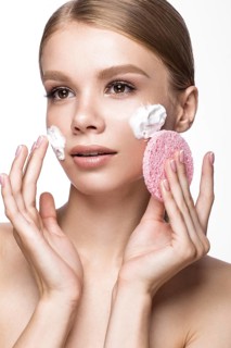 Beautiful young girl with sponge and foam cleanser and French manicure. Beauty face. Picture taken in the studio on a white background
