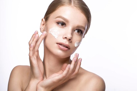 Beautiful young girl with cream on the skin and French manicure. Beauty face. Picture taken in the studio on a white background