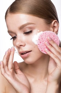 Beautiful young girl with sponge and foam cleanser and French manicure. Beauty face. Picture taken in the studio on a white background