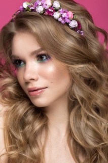Portrait of a beautiful blond girl in image of the bride with purple flowers on her head. Beauty face. Photo shot in the Studio