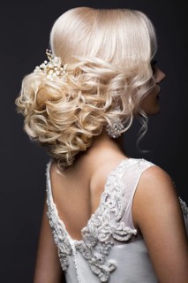 Portrait of a beautiful blond girl in image of the bride with wedding accessories on her head. Beauty face. Photo shot in the Studio on a grey background