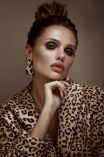 Beautiful sexy woman in a leopard coat and earrings
