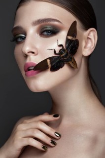Portrait of beautiful girl with colorful make-up and cicada. Beauty face. Photo taken in the studio