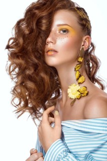 Portrait of beautiful red-haired girl with brightly colored art makeup and curls. Beauty face. Photo taken in the studio