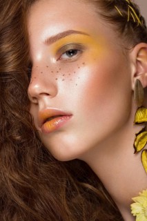 Portrait of beautiful red-haired girl with brightly colored art makeup and curls. Beauty face. Photo taken in the studio