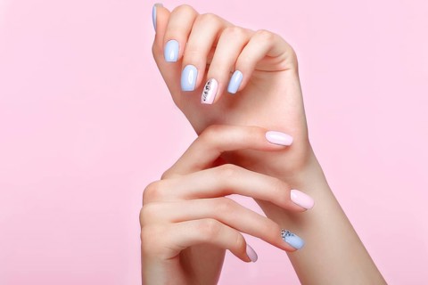 Beautiful pink and blue manicure with crystals on female hand. Close-up. Picture taken in the studio