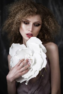 Beautiful girl with curly hair in lingerie with large flower. The beauty of the face. Photos shot in studio