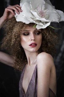 Beautiful girl with curly hair in lingerie with large flower. The beauty of the face. Photos shot in studio