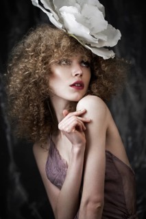 Beautiful girl with curly hair in lingerie with large flower. The beauty of the face. Photos shot in studio