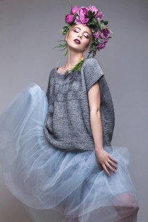 Beautiful girl with flowers on her head in fashion clothes posing against the background in the studio. Beauty Style