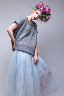 Beautiful girl with flowers on her head in fashion clothes posing against the background in the studio. Beauty Style