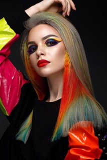 Beautiful girl with multi-colored hair and creative make-up and hairstyle. Beauty face. Photo taken in the studio