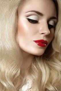 Beautiful blonde woman with evening make-up and red lips. Picture taken in the studio on a black background