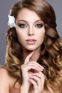 Portrait of a beautiful woman in the image of the bride with flowers in her hair. Picture taken in the studio on a grey background