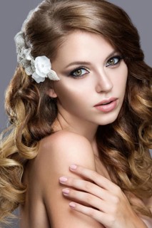 Portrait of a beautiful woman in the image of the bride with flowers in her hair. Picture taken in the studio on a grey background