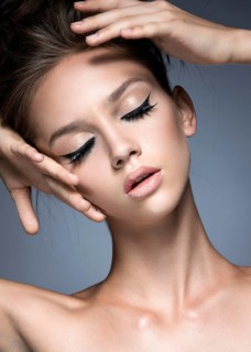 Beautiful girl with long eyelashes and perfect skin. Picture taken in the studio on a gray background. Beauty face