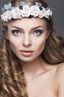 Portrait of a beautiful girl with a wreath of pink flowers on her head. Photo shot in the Studio on a grey background