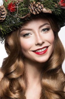 Beautiful girl with a wreath of Christmas tree branches and cones. New Year image. Beauty face. Picture taken in the studio on a white background