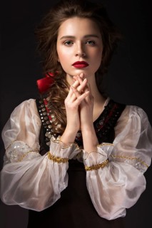 Beautiful Russian girl in national dress with a braid hairstyle and red lips. Beauty face. Picture taken in the studio on a black background