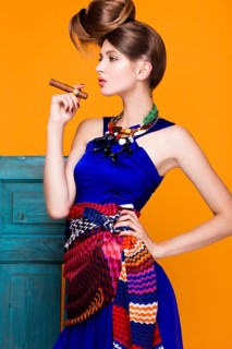 Beautiful fashionable woman an unusual hairstyle in bright clothes and colorful accessories. Cuban style. Picture taken in the studio on a bright background