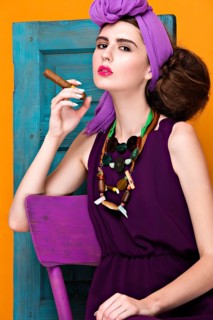 Beautiful fashionable woman an unusual hairstyle in bright clothes and colorful accessories. Cuban style. Picture taken in the studio on a bright background