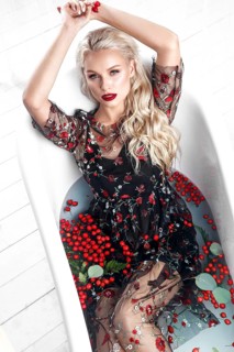 Beautiful girl in a summer dress in the bathroom with flowers. Beauty face. Photo taken in the studio