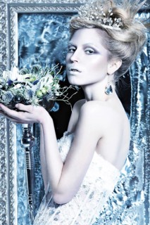 Beautiful girl in white dress in the image of the Snow Queen with a crown on her head. Picture taken in the studio with decorations