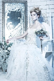 Beautiful girl in white dress in the image of the Snow Queen with a crown on her head. Picture taken in the studio with decorations