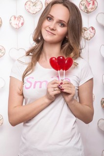 Valentines Day. Funny beautiful Woman holding candy in the form of heart. Beauty face. Picture taken in the studio with decorations