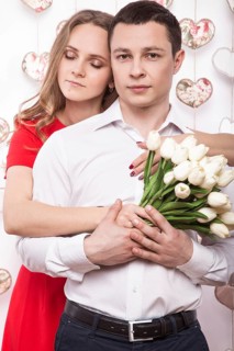 Beautiful young couple in love with a bouquet of flowers. Valentine's Day. Picture taken in the studio