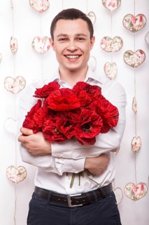 Beautiful young man in love with a bouquet of flowers. Valentine's Day. Picture taken in the studio