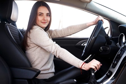 Young beautiful happy woman sitting at the wheel new car