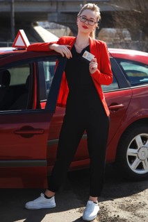 Joyful girl driving a training car with a drivers license card in her hands