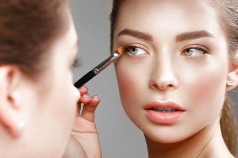 Beautiful girl makes herself a make-up in the mirror. Beauty face. Photo taken in studio