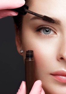 Close-up of female eyes with an eyebrow brush. Eye makeup cosmetics