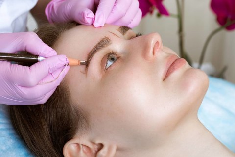 Permanent microblasting tattooing freckles to a woman in a beauty salon