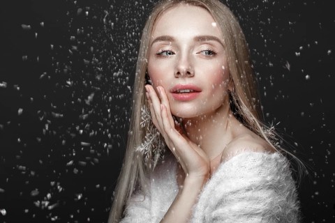 Beautiful blonde girl in a winter image with snow. Beauty face. Photo taken in the studio