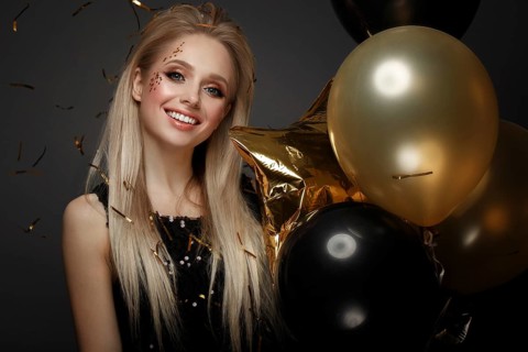 Beautiful young girl in elegant evening dress with festive balloons. Beauty face. Photo taken in the studio