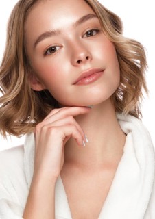 Beautiful tender young girl in a white coat with clean fresh skin posing in front of the camera. Beauty face. Skin care. Photo taken in studio on a white isolate background