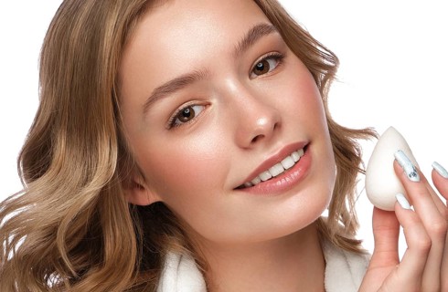 Beautiful tender young girl in a white coat with clean fresh skin posing in front of the camera. Beauty face. Skin care. Photo taken in studio on a white isolate background