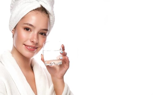 Beautiful tender young girl in a white towel with clean fresh skin posing in front of the camera. Beauty face. Skin care. Photo taken in studio on a white isolate background