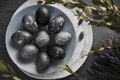 Black painted eggs for Easter on a blue plate