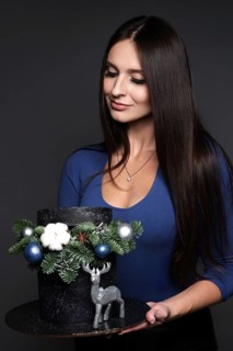 Beautiful woman pastry chef in a blue dress with a Christmas cake in her hands