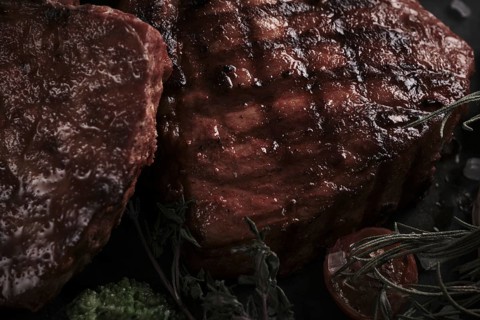 Piece of appetizing pork steak on the bone with vegetables in vintage style