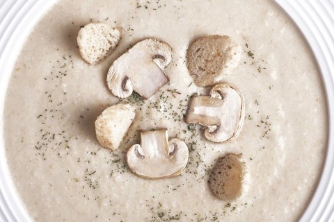 Creamy chicken soup with mushrooms on a white plate