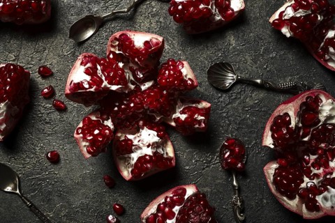 Metal background with pomegranate berries and retro spoons. Vintage style photo