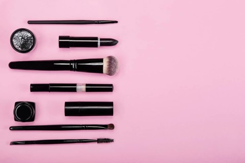 Set of brushes and cosmetic products on a pink background