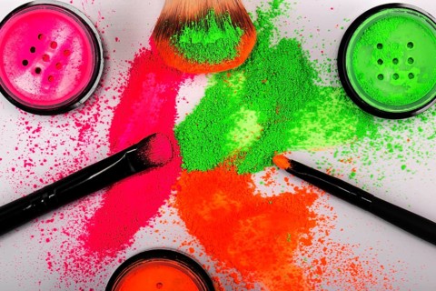 Cheek brush with neon cosmetic powder colorful pile and isolated on white background