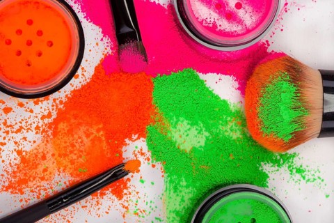 Cheek brush with neon cosmetic powder colorful pile and isolated on white background