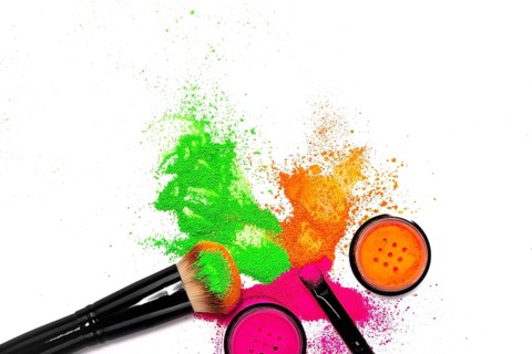 Cheek brush with neon cosmetic powder colorful pile and isolated on white background